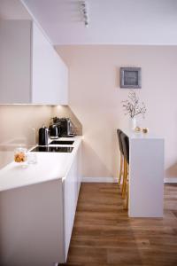 a white kitchen with a counter and a table at Apartament Bimba - Free Parking in Poznań