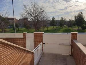 una valla blanca con una pared de ladrillo y árboles en Chalet IFema 5 Habitaciones 4 baños, parking free en Madrid