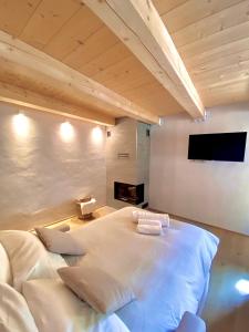 een slaapkamer met een groot wit bed en een open haard bij Courmayeur Superior Suite by SupaStays in Courmayeur