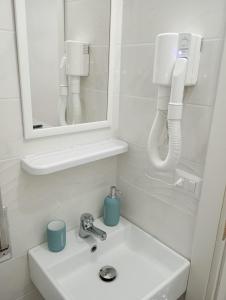 ein weißes Badezimmer mit einem Waschbecken und einem Spiegel in der Unterkunft Il Focolare in Focene