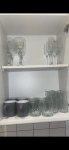 a shelf with glasses and bowls and other dishes at Spacious apartment in Barking