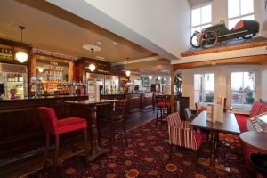 eine Bar mit roten Stühlen und Tischen in einem Restaurant in der Unterkunft The Foley Arms Hotel Wetherspoon in Great Malvern