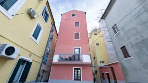 a pink building with a balcony in an alley at Alicetta Apartment by Ca-Sa Check in Chioggia