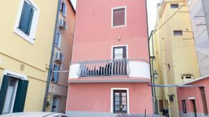 a pink building with a balcony on a street at Alicetta Apartment by Ca-Sa Check in Chioggia +32 photos