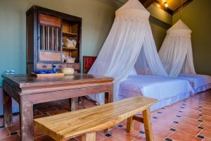 a bedroom with two beds and a table and a bench at Murraya Paniculata Villa in Magong