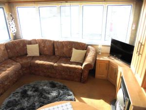 a living room with a brown couch and a flat screen tv at 6 Berth Sealands Ingoldmells Free WIFI Westmorland SL in Ingoldmells