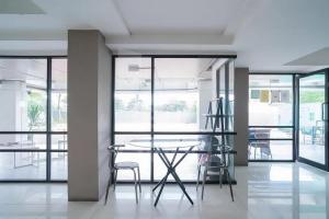 uma sala de jantar com mesa, cadeiras e janelas em RedLiving 19 Avenue Apartment by RH Room em Tangerang