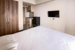 um quarto com uma cama branca e uma televisão na parede em RedLiving 19 Avenue Apartment by RH Room em Tangerang
