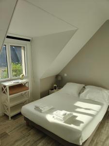 a bedroom with a white bed and a window at Hôtel Restaurant La Voile Bleue in Erdeven