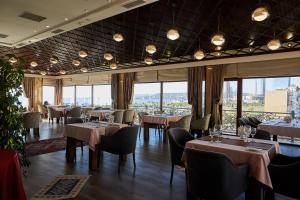 un restaurante con mesas, sillas y ventanas grandes en Boulevard Side Hotel en Baku