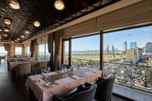 a restaurant with tables and chairs and large windows at Boulevard Side Hotel in Baku