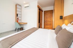 a bedroom with a large bed with a desk and a chair at Sunny Village Berawa in Canggu