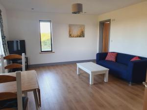a living room with a blue couch and a table at Roaringwater Stay in Skibbereen