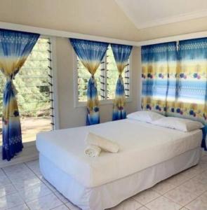 a bedroom with a large white bed with blue curtains at Bay of Plenty Nature Lodge in Nanuya Lailai