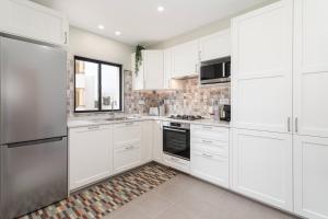 a kitchen with white cabinets and a stainless steel refrigerator at Great, Bright 2-bedroom Flat in the Center of Vilamoura -Topázio By Centralgarve in Vilamoura