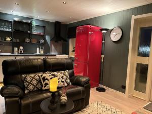 a living room with a leather couch and a red refrigerator at Ett roms leilighet Vestvågøy in Gravdal