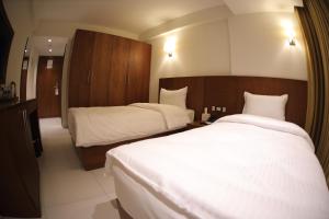Habitación de hotel con 2 camas con sábanas blancas en Coral Hotel Karbala en Karbala