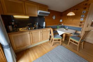 eine Küche mit einem Tisch, Stühlen und einem Waschbecken in der Unterkunft Pension Zirbenhof in Ramsau am Dachstein