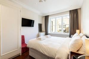 - une chambre avec un grand lit blanc et une fenêtre dans l'établissement 1BR Chic Covent Garden Retreat, à Londres