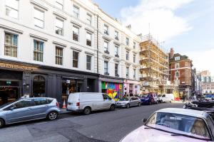 une rue urbaine animée avec des voitures garées dans la rue dans l'établissement 1BR Chic Covent Garden Retreat, à Londres