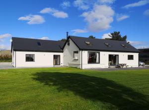 a white house with a black roof on a grass field at Roaringwater Stay in Skibbereen