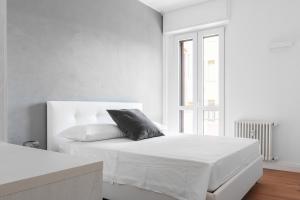 een witte slaapkamer met een bed met een zwart kussen bij Pure White - by MyHomeInComo in Como