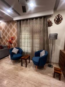 a living room with two blue chairs and a lamp at Kamz Homestay Chandigarh 35 in Chandīgarh