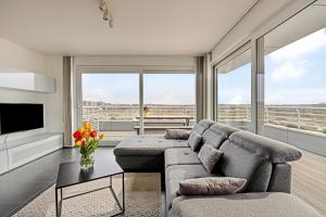 een woonkamer met een bank en een tv bij Karthuizer Penthouse in Nieuwpoort