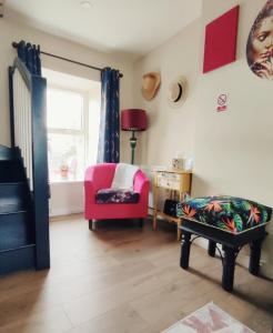 sala de estar con silla rosa y ventana en Unboring Holiday Let, Ballina, Mayo en Ballina