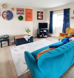 a living room with a blue couch and a tv at Unboring Holiday Let, Ballina, Mayo in Ballina