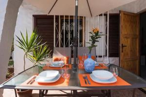 a table with plates and glasses and an umbrella at Bungalow Ubicación Ideal in San Bartolomé de Tirajana
