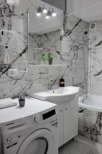 ein weißes Badezimmer mit einer Waschmaschine und einem Waschbecken in der Unterkunft Deluxe Apartments on G Enescu Blvd near Stefan Cel Mare University Suceava in Suceava