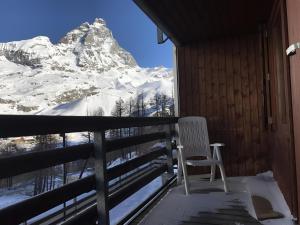 een witte stoel op een balkon met een met sneeuw bedekte berg bij Condominio La Grand'Ourse - Cervinia in Breuil-Cervinia