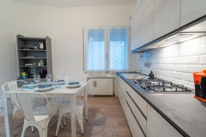 cocina blanca con mesa y fogones en Art Gallery Rimini Apartments 130mq Esclusivo, en Rímini