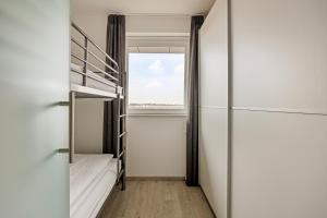 een kamer met een stapelbed en een raam bij Karthuizer Penthouse in Nieuwpoort