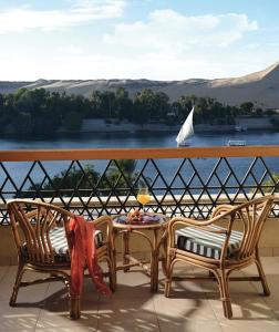 a balcony with a table and two chairs and a sailboat at Mövenpick Resort Aswan in Aswan