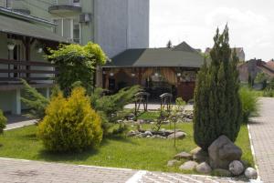 um jardim com árvores e arbustos em frente a um edifício em Hotel Perla em Satu Mare