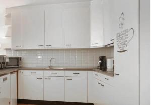 a white kitchen with white cabinets and a sink at Appartement Groot, Hartje Centrum, Colline's in Tilburg