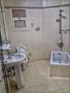 a bathroom with a sink and a toilet and a tub at Lazorde Bay Apartment in El Alamein