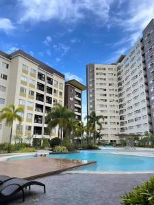 a swimming pool in front of two large buildings at Stylish 2Bedroom Unit @Avida #26 in Iloilo City
