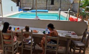 three women sitting at a table in front of a swimming pool at Casa Vignali country house in Augusta