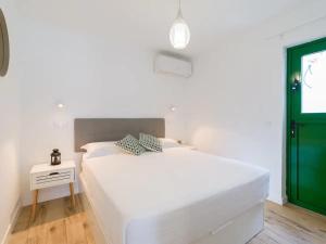 ein weißes Bett in einem Zimmer mit grüner Tür in der Unterkunft Elegante apartamento 5 min de playa in San Bartolomé de Tirajana