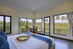 a bedroom with a large bed and large windows at Nang Ade Villa by Pramana Villas in Ubud