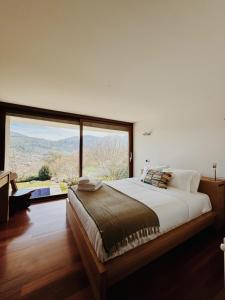 a bedroom with a large bed and a large window at Quinta Trindade in Arouca
