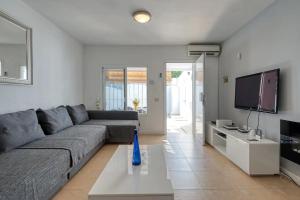 ein Wohnzimmer mit einem grauen Sofa und einem TV in der Unterkunft Amplio Apartamento en el centro in San Bartolomé de Tirajana