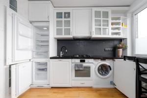 cocina con armarios blancos, lavadora y secadora en Angel House Vilnius, Skroblu 39 en Vilna