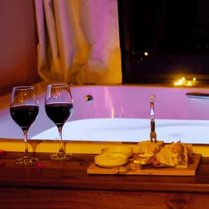 2 bicchieri di vino seduti accanto a una vasca da bagno di Chalé Vista do Paraíso a Gonçalves