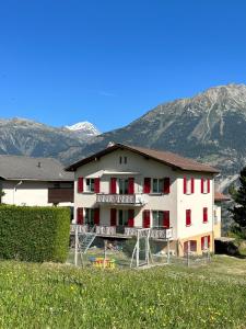 duży biały budynek z czerwonymi oknami i górami w obiekcie Wohnung Christania 3200 Unterbäch Wallis w mieście Unterbäch