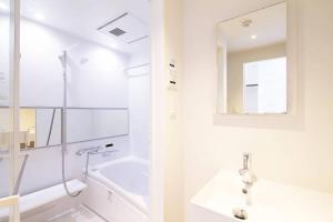 y baño blanco con lavabo y bañera. en bHOTEL Komachi - Apt for 6ppl few mins walk to Peace Park en Hiroshima