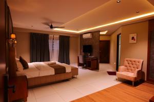 KānnangādHotel Classico International的一间带床和椅子的酒店房间